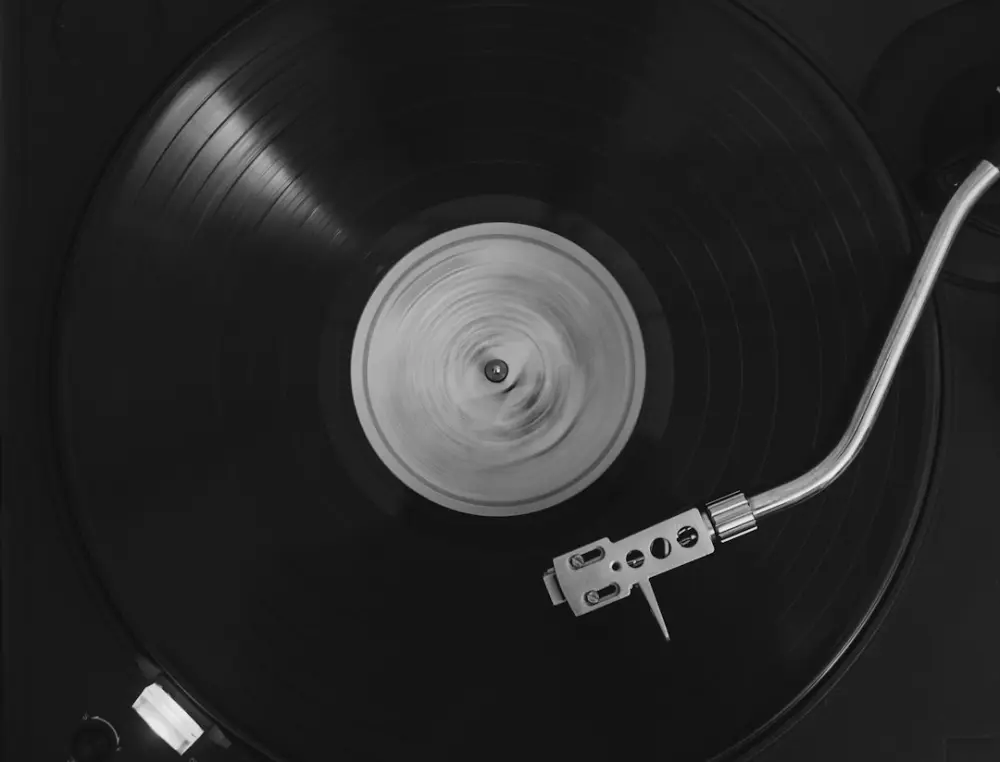 A black vinyl record spinning on a turntable with a silver tonearm, illustrating understanding jazz sounds through examples